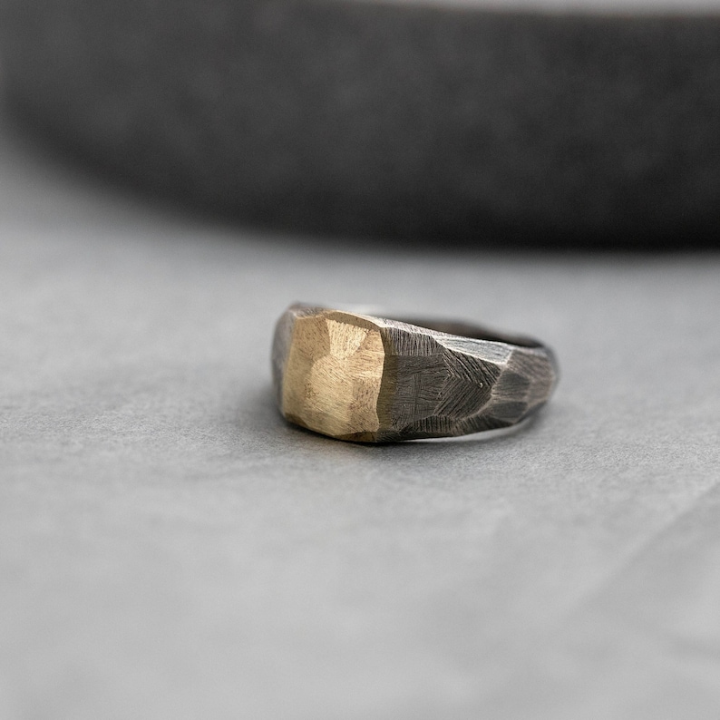 Brutalist signet ring for men and women in sterling silver with real 14K gold on top. The ring is faceted by hand and it is darkened for a more rough style.