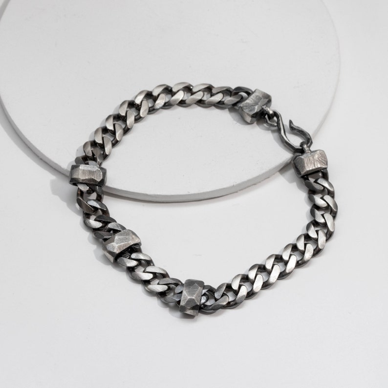 A sterling silver Cuban link chain bracelet with scratched links for men in black oxidized silver
