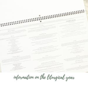 May include: A white spiral-bound calendar open to a page with detailed text. The text is arranged in columns and blocks, with the words "information on the liturgical year" at the bottom. The calendar is on a light-colored surface.