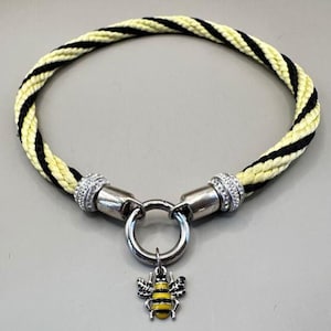 Peut inclure: Un collier de chien en corde jaune et noir avec un charme d'abeille argenté. Le collier a une boucle argentée et un anneau argenté.