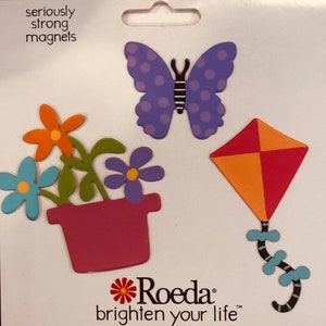 Pode incluir: Um conjunto de três ímãs coloridos que representam uma borboleta, uma pipa e um vaso de flores. Os ímãs são feitos de madeira e têm um acabamento pintado. A borboleta é roxa com bolinhas brancas, a pipa é vermelha e laranja, e o vaso é rosa com folhas verdes e flores coloridas.