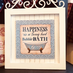 May include: White framed picture with a blue and white patterned background. The picture says "Happiness is a long hot bubble bath" with a vintage style illustration of a bathtub.
