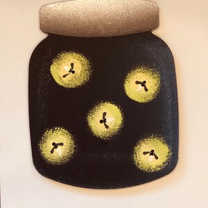 May include: A black jar with a silver lid and a white background. The jar is filled with yellow fireflies. The text "Roeda brighten your life" is printed below the jar.