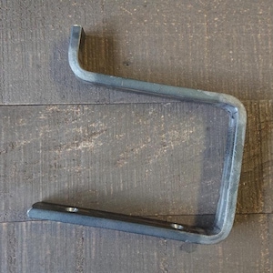 May include: A metal shelf bracket with a simple, industrial design. The bracket is made of sturdy metal and has a black finish.