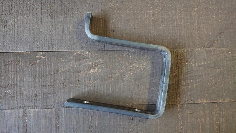 May include: A metal shelf bracket with a simple, industrial design. The bracket is made of sturdy metal and has a black finish.