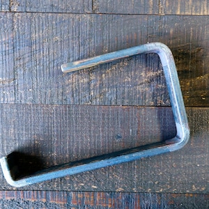 May include: A metal shelf bracket with a simple, industrial design. The bracket is made of sturdy metal and has a raw, unfinished look.