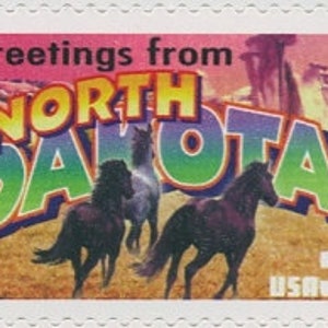 May include: A vintage-style postcard featuring a colourful "Greetings from North Dakota" design with a scenic landscape and a group of horses running across a field. The postcard is dated 2002 and has a US postage stamp with the value 34 cents.