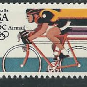 May include: A vintage USA 35-cent airmail postage stamp from the 1984 Olympics. The stamp features a cyclist in motion on a red bicycle, with the Olympic rings and text "Olympics 84" and "USA" in black.