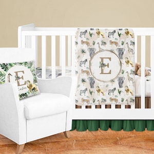 May include: A white crib with a green and brown safari-themed bedding set. The bedding features a blanket with a repeating pattern of animals, including lions, zebras, elephants, and giraffes. The blanket also has a gold circle with the letter "E" in the center. A white armchair with a matching pillow featuring the same safari pattern and the letter "E" is in the foreground.