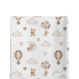 Könnte beinhalten: Ein weißes Babybettlaken mit einem sich wiederholenden Muster aus braunen Teddybären, Wolken, Sternen, Heißluftballons und Mondsicheln. Das Muster befindet sich auf weißem Hintergrund.