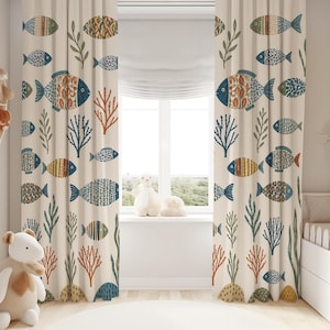 May include: Two floor-length curtains featuring a repeating pattern of various fish and coral in shades of blue, orange, yellow, and green on a cream background. The fabric drapes vertically, covering the sides of a window in a room.