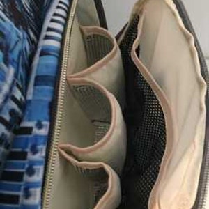 May include: The inside of a blue and white patterned diaper bag with multiple pockets and a mesh compartment.
