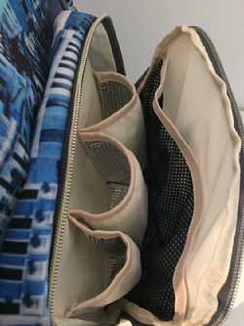 May include: The inside of a blue and white patterned diaper bag with multiple pockets and a mesh compartment.
