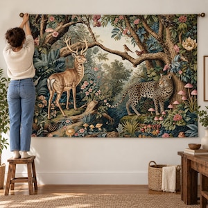 May include: A large rectangular wall tapestry featuring a detailed forest scene with a brown deer standing on the left and a spotted leopard standing on the right. The landscape includes dense trees, pink flowers, small mushrooms, and birds.