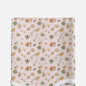 May include: A pink fabric with a repeating pattern of brown bears, deer, flowers, and leaves. The pattern is a watercolor style.