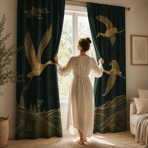 May include: A pair of floor-length dark green curtains featuring a gold-coloured print of flying cranes and a landscape scene at the bottom. The curtains are hung on a gold rod and are parted to reveal a window with natural light coming through.