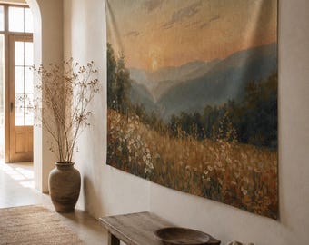 May include: A rectangular wall tapestry featuring a landscape painting of a sunset over rolling mountains and a field of wildflowers in shades of gold, green, and soft orange. The artwork is displayed hanging flat against a neutral-colored wall.