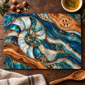 May include: A rectangular cutting board featuring a large, iridescent nautilus shell design in shades of blue, teal, and gold. The surface displays a wood grain pattern and a circular laurel wreath emblem with the text WILLIAMS in the corner.