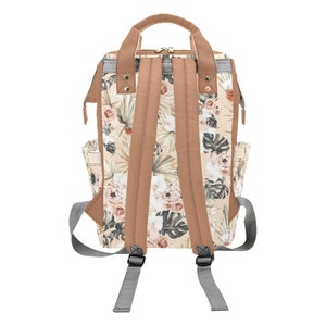 May include: A beige and brown floral print backpack with adjustable straps. The backpack has a zipper closure and two side pockets.
