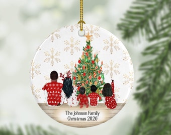 May include: A round, white ceramic Christmas ornament with a gold snowflake pattern. The ornament features a family of four, a Christmas tree, and the text "The Johnson Family Christmas 2020".