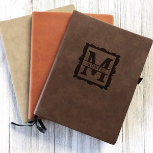 May include: Three leather-bound journals in brown, tan, and rust colors. The brown journal has a personalized monogram with the letter "M" and the name "MONTEZ" engraved on the front cover.