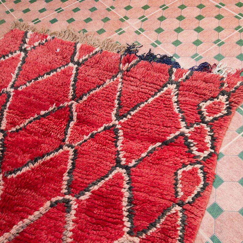 May include: A red and black Moroccan rug with a geometric pattern. The rug is made of wool and has a soft, plush texture.