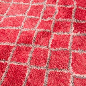 May include: A red and gray patterned rug with a fluffy texture. The rug has a geometric design with squares and diamonds.