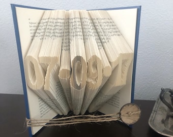 May include: A book with pages folded into the shape of the numbers "07.08.17". The book is blue and has a brown twine tied around it.