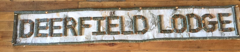 custom personalized sign made with twigs backed with birch bark.