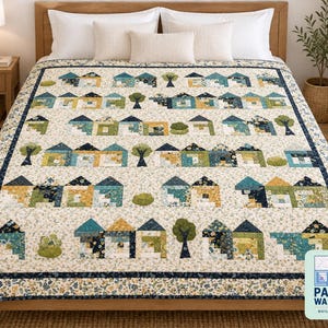 Op de afbeelding: Een quilt met een herhalend patroon van huizen en bomen in tinten blauw, groen en geel op een cr&egrave;mekleurige bloemenachtergrond. De quilt heeft een donkerblauwe rand en bevat het logo van Pattern Warehouse in de hoek.