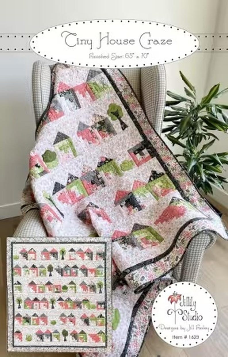 Op de afbeelding: Een quilt getiteld Tiny House Craze met een afgewerkte maat van 165,1 cm bij 177,8 cm. De quilt heeft een herhalend patroon van kleine huisjes in roze, groene en zwarte tinten op een lichte achtergrond, met een donkere rand en Jillily Studio merk.