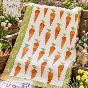 May include: A rectangular quilt featuring a repeating pattern of orange carrots with green tops on a white background, framed by a light green floral border. The quilt is draped over a wooden surface, showcasing a quilted texture throughout.