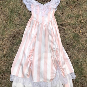 May include: A pink and white striped dress with a lace bodice and trim. The dress has a fitted bodice and a full skirt.