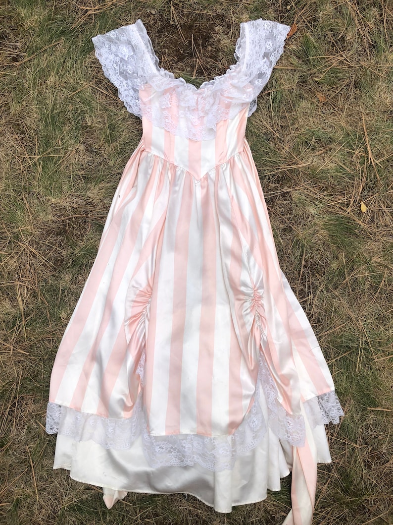 May include: A pink and white striped dress with a lace bodice and trim. The dress has a fitted bodice and a full skirt.