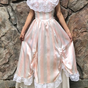 May include: A long, pink and white striped satin dress with a white lace bodice and a white lace trim around the hem. The dress has a fitted bodice and a full skirt.