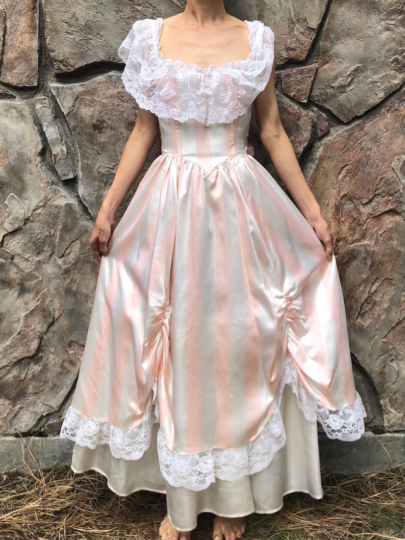 May include: A long, pink and white striped satin dress with a white lace bodice and a white lace trim around the hem. The dress has a fitted bodice and a full skirt.