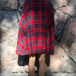 May include: A red, green, and white plaid cape with a long, flowing design.