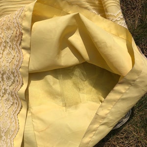 May include: A yellow skirt with a lace trim and a tulle lining. The skirt is made of a lightweight fabric and has a flowy silhouette.