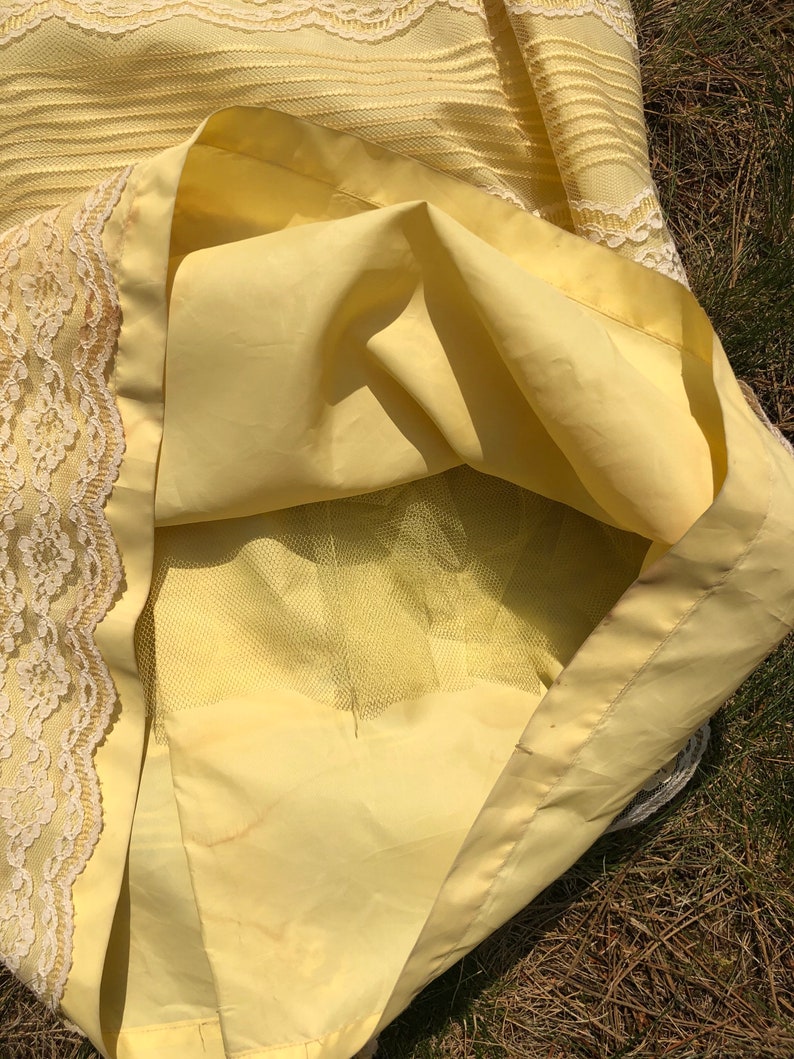 May include: A yellow skirt with a lace trim and a tulle lining. The skirt is made of a lightweight fabric and has a flowy silhouette.