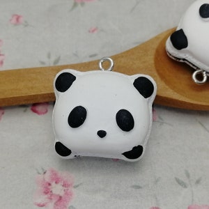 May include: Two white panda bear charms with black eyes and ears. The charms are made of polymer clay and have a hole for attaching a chain or string.