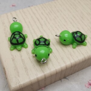 Puede incluir: Tres abalorios de tortuga verde con detalles de caparazón negro. Los abalorios tienen anillas de salto plateadas para sujetarlos a joyas u otras manualidades.