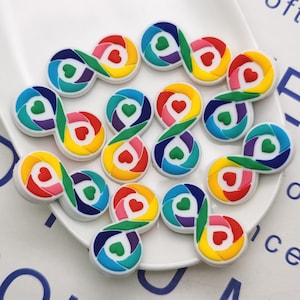 Puede incluir: Una colección de 12 dijes de símbolo de infinito de colores arcoíris con un corazón en el centro. Los dijes están hechos de silicona y son perfectos para agregar un toque de color a tus joyas o manualidades.