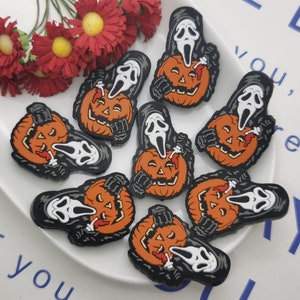 Op de afbeelding: Acht Halloween-charms met een spookgezichtsmasker dat een jack-o'-lantern vasthoudt. De charms zijn gemaakt van zwart, oranje en wit hars.