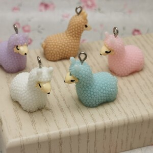 May include: Five small llama charms in different colors: light blue, white, pink, light purple, and beige. Each charm has a silver loop for attaching to a necklace, bracelet, or other jewelry.