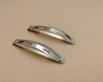 May include: Two silver metal hair clips. The clips are curved and have a smooth, shiny finish.