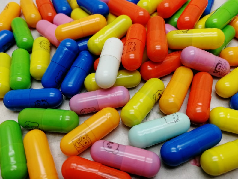 May include: A large pile of colorful capsules with various cartoon characters printed on them. The capsules are made of plastic and are about 2 inches long.