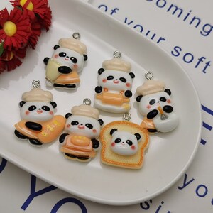 May include: Six panda bear charms with orange and white accents. The charms are made of resin and have a hole for attaching to a necklace or bracelet. The charms are shaped like pandas wearing chef hats and holding various food items.