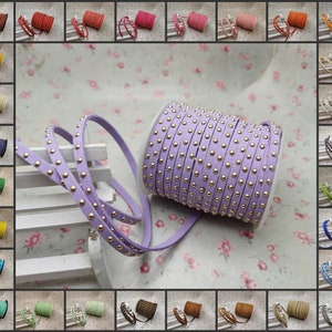 Può includere: Un rotolo di cordoncino in pelle color lavanda con borchie dorate. Il cordoncino è avvolto su una bobina ed è pronto per essere utilizzato per progetti di artigianato.