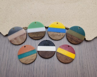 May include: Eight round wooden ornaments with different colored resin layers. The ornaments have a hole at the top for hanging. The colors include green, white, black, blue, yellow, red, orange, and brown.