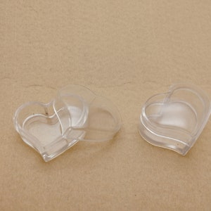 Op de afbeelding: Drie transparante, hartvormige doosjes van plastic. De doosjes zijn in elkaar genest.